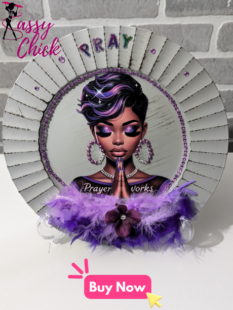 A handcrafted decorative charger featuring a purple theme with a depiction of a female figure in prayer pose, surrounded by feather-like designs and the word 'PRAY' in uppercase letters.