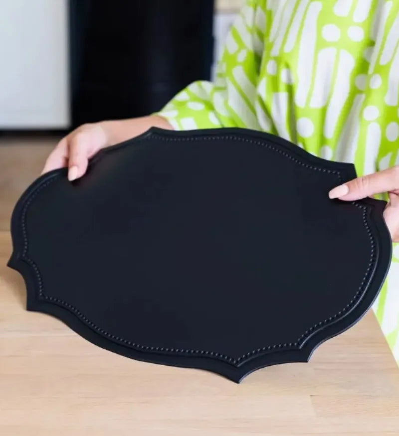 Shaped faux leather PU placemat set in black, pink, and green on a dining table