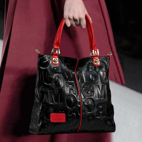 holding black red letter patter handbag